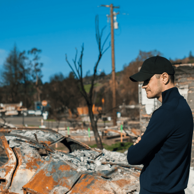 Man staring at wreckage from natural disaster